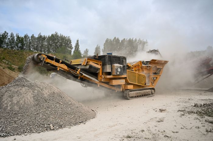 Mobile crusher working in a quarry with dust rising